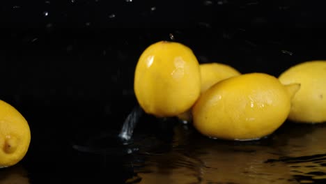 whole fresh lemons falling in water splashes.