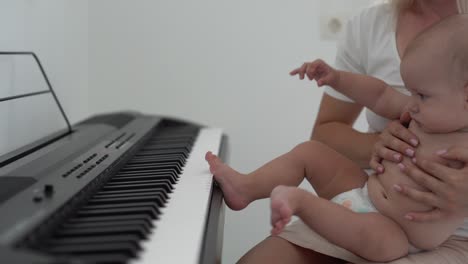 mother and toddler baby boy, playing piano at home, child learning