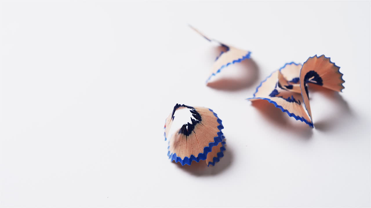 primer plano de virutas de lápiz azul con espacio de copia sobre fondo blanco, en cámara lenta