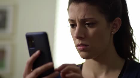 A young woman with a concerned expression checks her smartphone in a well-lit room. She appears anxious as she reads a message that has captured her attention.