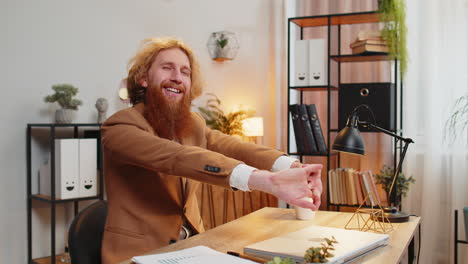 businessman closing laptop stretching arms after finishing work at home office desk working online