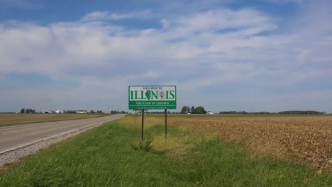 el cartel a lo largo de un camino rural abandonado a través del campo indica la línea estatal de illinois