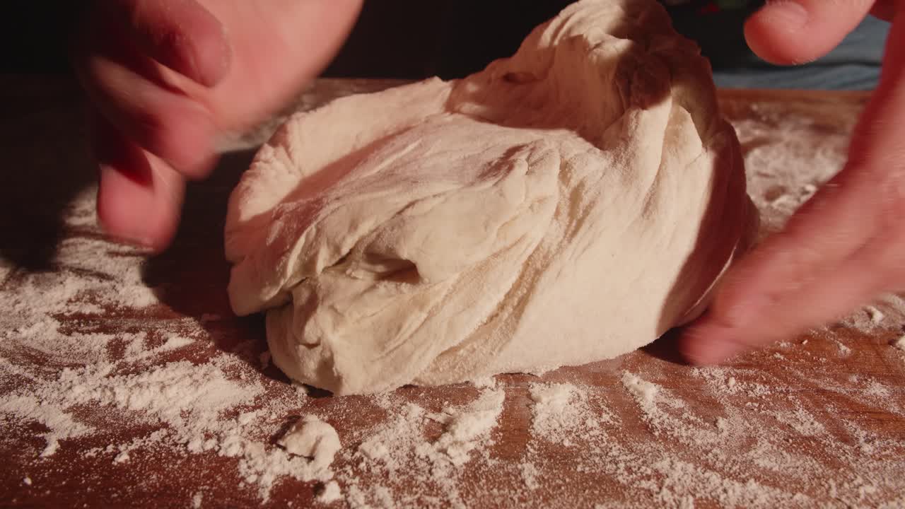 Mani che impastano l'impasto su un tagliere di legno infarinato