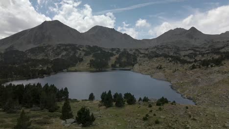 Drone-view-arriving-to-the-lake-in-front-of-the-mountains