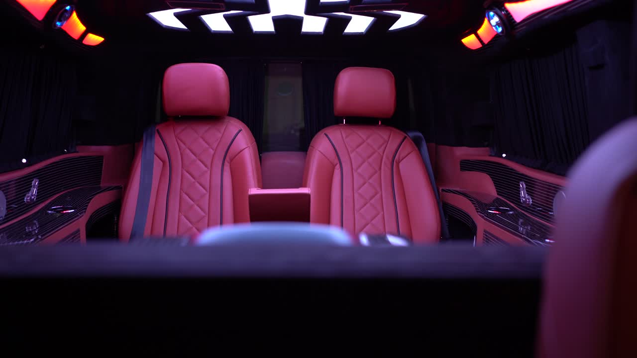 A luxurious car interior of a limousine or business van with red seats and a nice roof lighting. This clip was shot at night to demonstrate the nice LED lighting in this car. The clip is shot in UHD