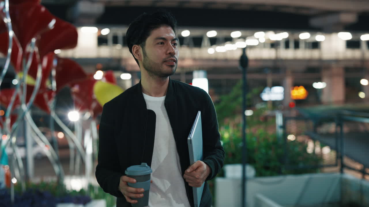 Man Walking at Night with Laptop and Coffee