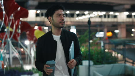 man walking at night with laptop and coffee