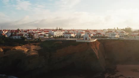 aerial shot of a town at sunset along the west coastal cliffs in portugal