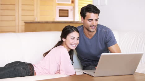 una pareja sonriente mirando una computadora portátil