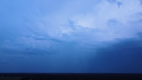 beautiful aerial view of dramatic dark thunder storm clouds in summer evening, extreme thunderstorm with spectacular lightning strike flash through the clouds, distant wide angle drone tilt up shot