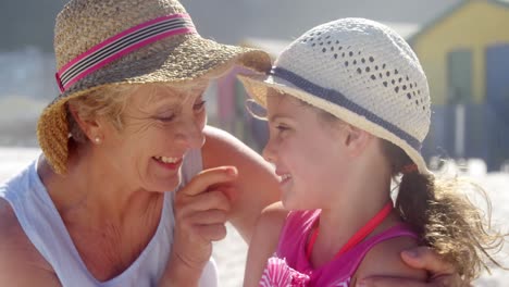 Grandmother-and-granddaughter-playing-with-each-other-at-beach