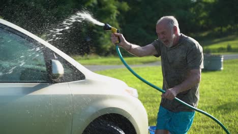 crazy man with hose washing car and flailing water in the air in slow motion