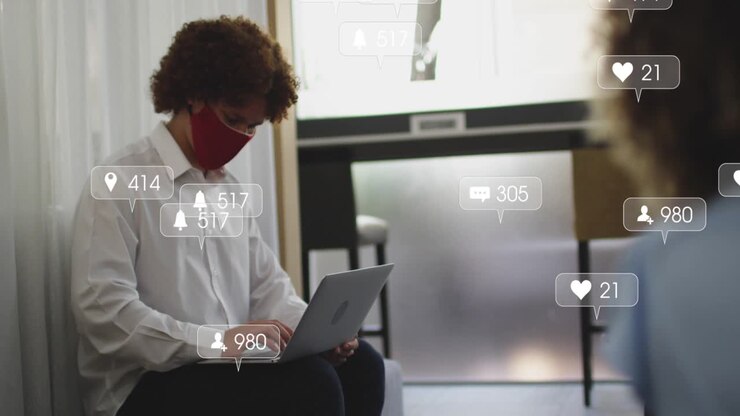 Seated man typing on laptop causing social icons growing around him, red mask showing engagement up