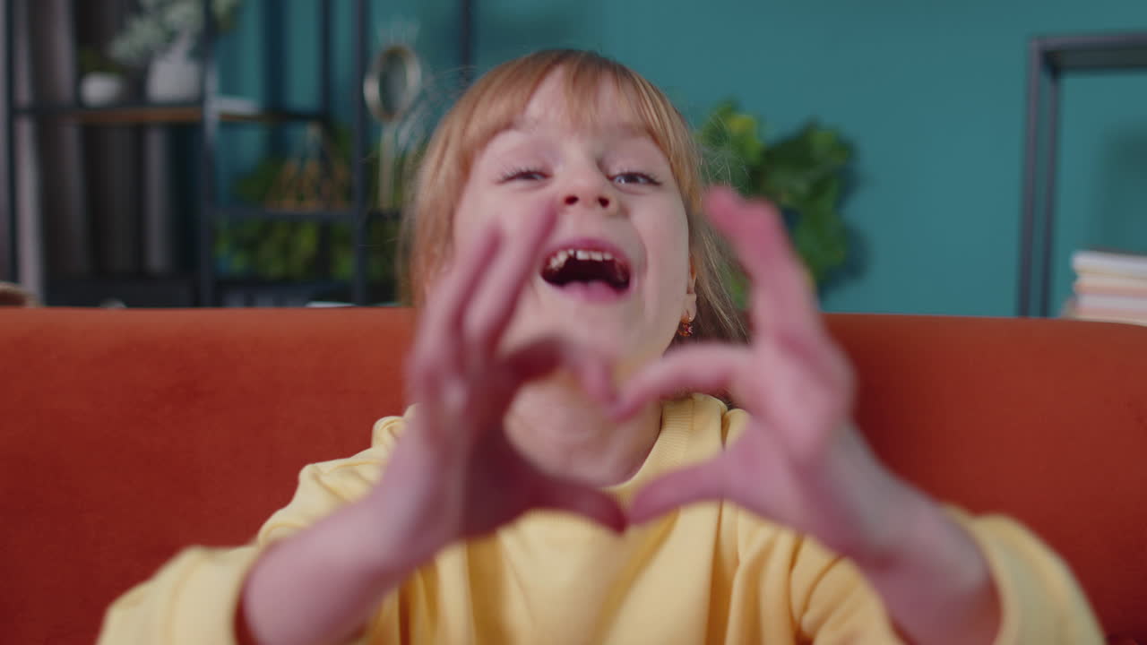 미소 짓는 아이, 소파에 앉아 카메라를 바라보는 아이, 심장 동작, 사랑의 표시