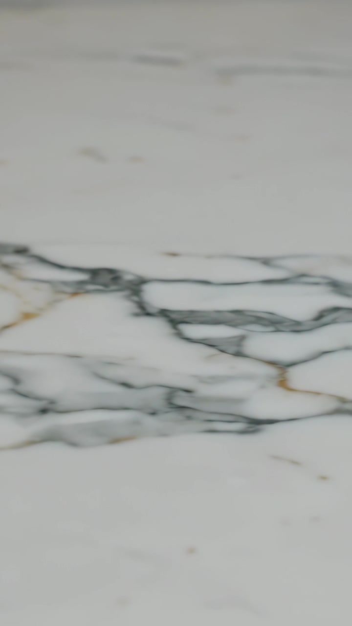 Vertical video: Panning camera revealing white marble slab on counter while showing grey gold veins