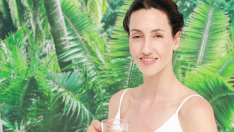 Pretty-brunette-holding-a-cup-of-herbal-tea-