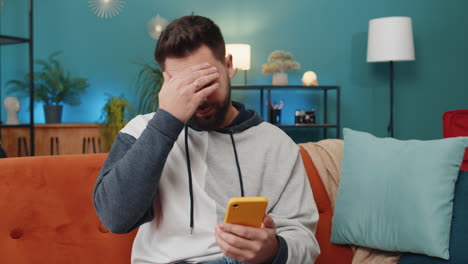 sad young man use smartphone surprised by bad news, fortune loss, fail, lottery results, deadline