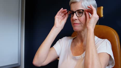 senior woman adjusting eyeglasses in clinic 4k