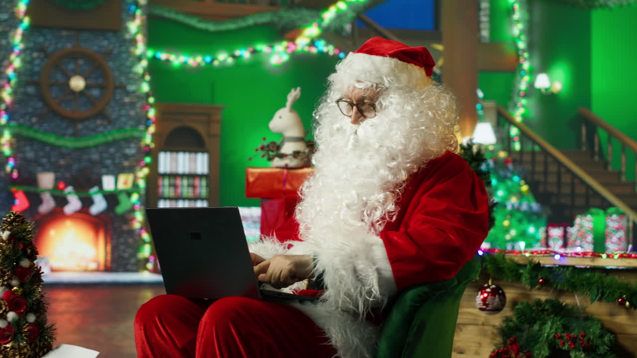 산타클로스가 크리스마스 동안 노트북에서 일하고 있습니다.