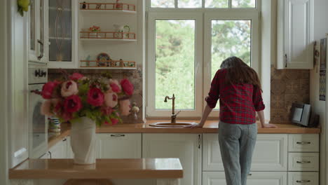 crying woman stands by kitchen window. brokenhearted wife hides tears leaning on countertop at home. lady deals with hard grief of husband death