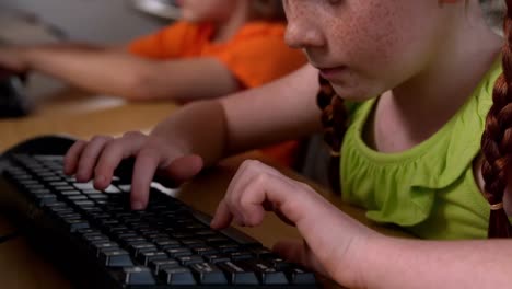 Little-girl-using-computer-in-classroom-in-school