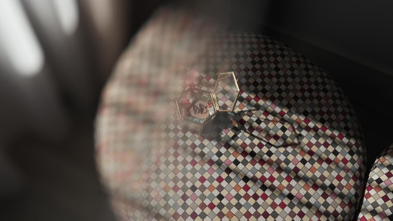 golden hexagonal ring box with initials on patterned surface lit by soft morning light