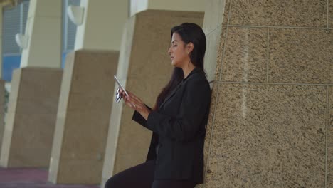 Joven-Latina-Se-Apoya-En-Una-Pared-En-La-Ciudad-Caribeña-De-Trinidad,-Puerto-España-En-Traje-De-Negocios