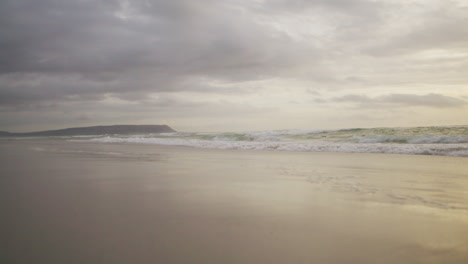 Wide-Shot-of-beach-with-Waves-coming-onto-shore-at-Sunset-shot-in-4K-ProRess-422