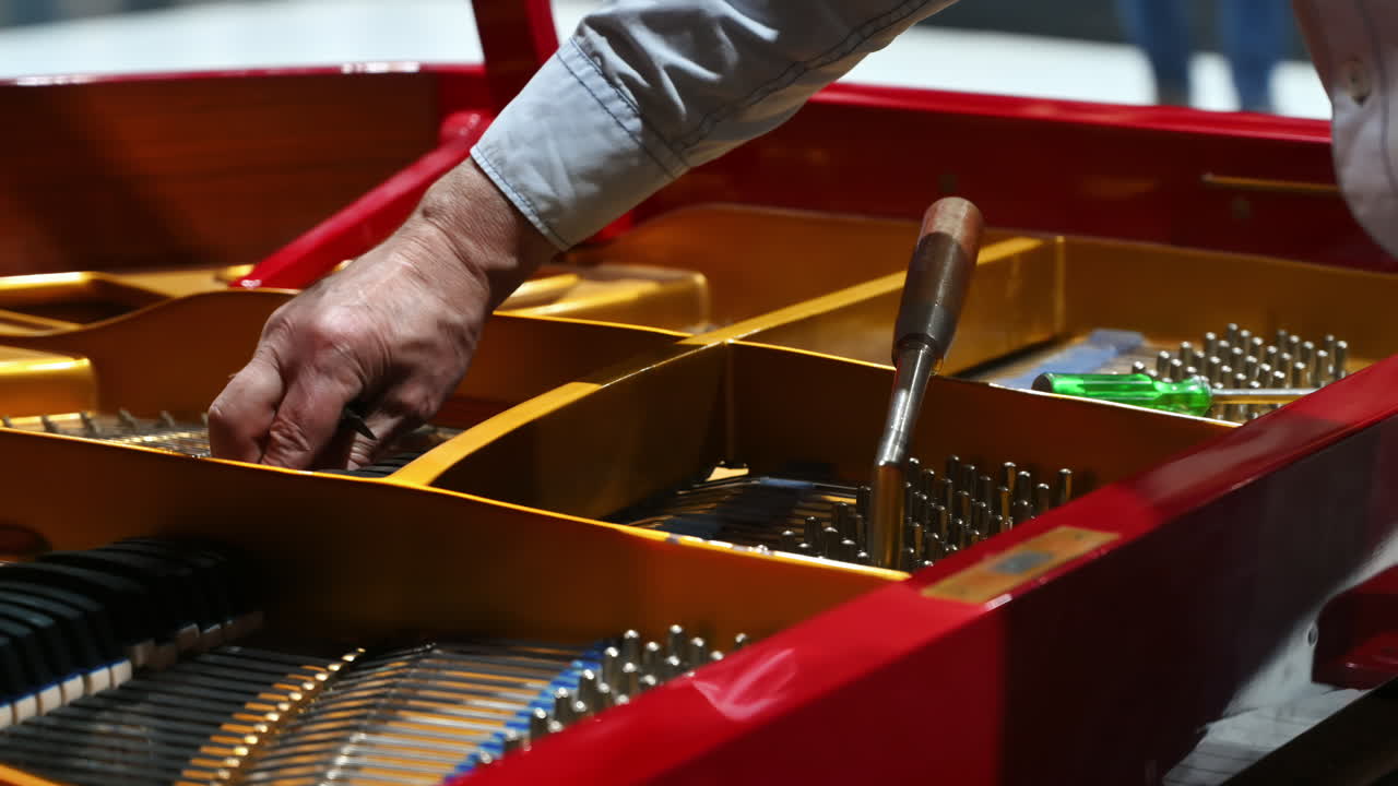 Close up of a man fixing a red piano