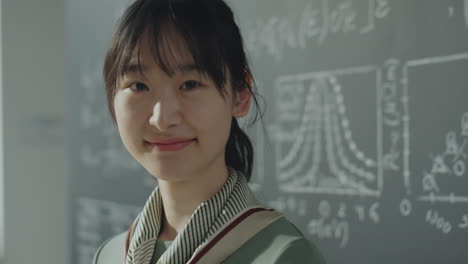smiling young woman in front of a science chalkboard