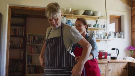 Smiling-senior-caucasian-couple-wearing-aprons-and-preparing-before-cooking-in-kitchen