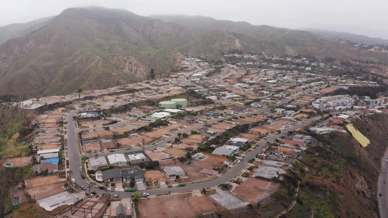 Wide reverse pullback aerial shot of burned lots in the Sunset Mesa neighborhood after the Palisades wildfire in Malibu, California. 4K