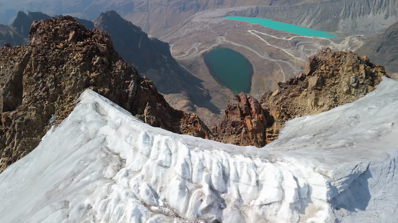 Aerial parallax shot from above reveals Montaña Mateo’s icy summit and dramatic Andean landscape with glacial lakes below