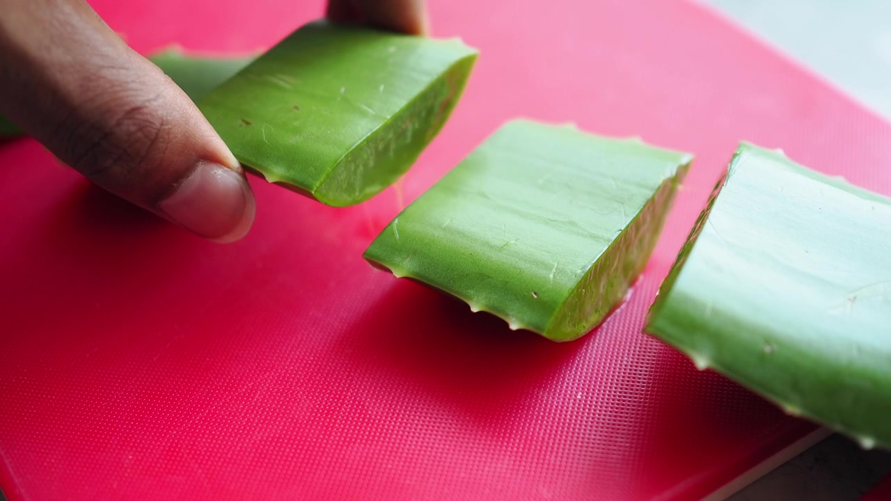 Mano che prende una fetta fresca di Aloe Vera