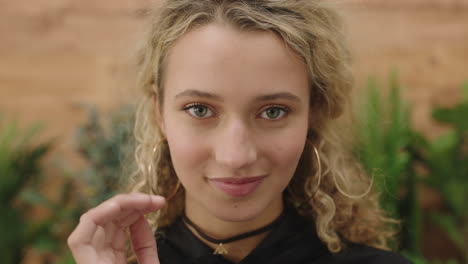 close up portrait of pretty young blonde woman smiling cute looking at camera running hand through hair