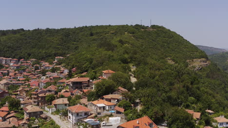 drone flies over wooded hilltops above veliko tarnovo hillside historic city