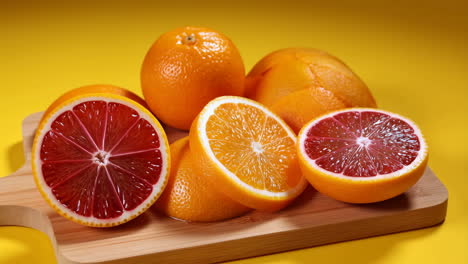 Fresh Oranges on a Cutting Board with Yellow Background