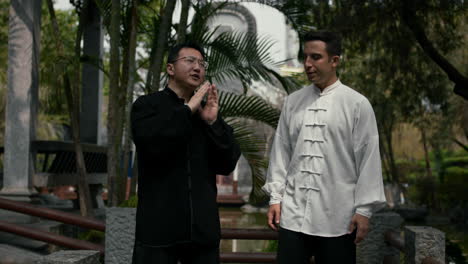 two men in traditional chinese attire discuss in a tranquil garden setting