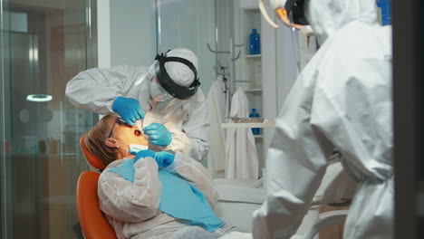 dentist with face shiled treating teeth to senior woman