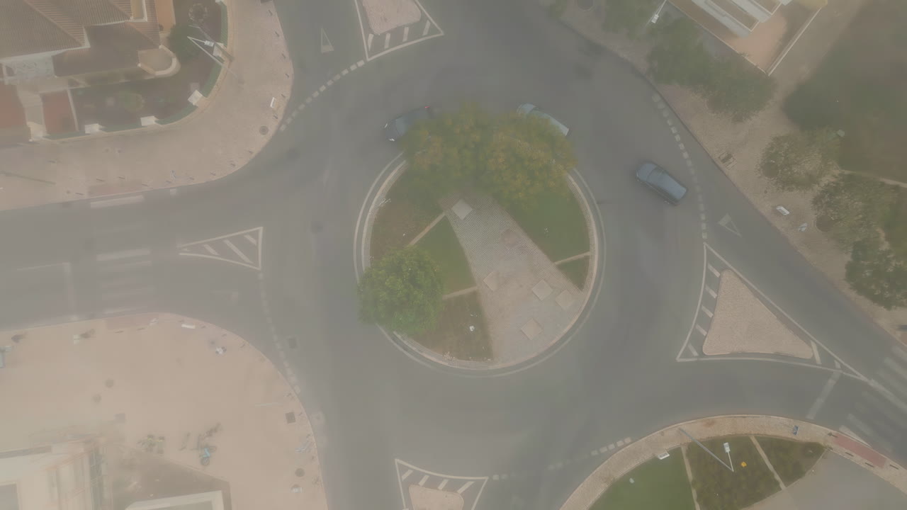Aerial foggy urban roundabout with cars riding road. Top shot green roadway ring