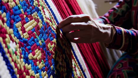 close-up of a woman weaving a colorful carpet