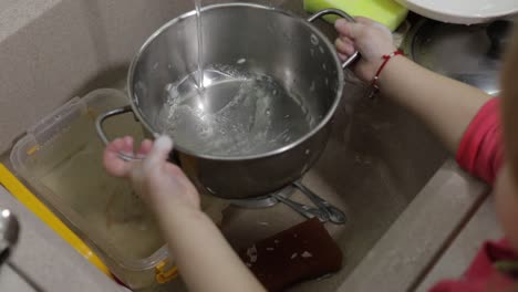 Niño-Lavando-Platos-En-La-Cocina.-Primer-Plano-De-Las-Manos-De-Las-Niñas