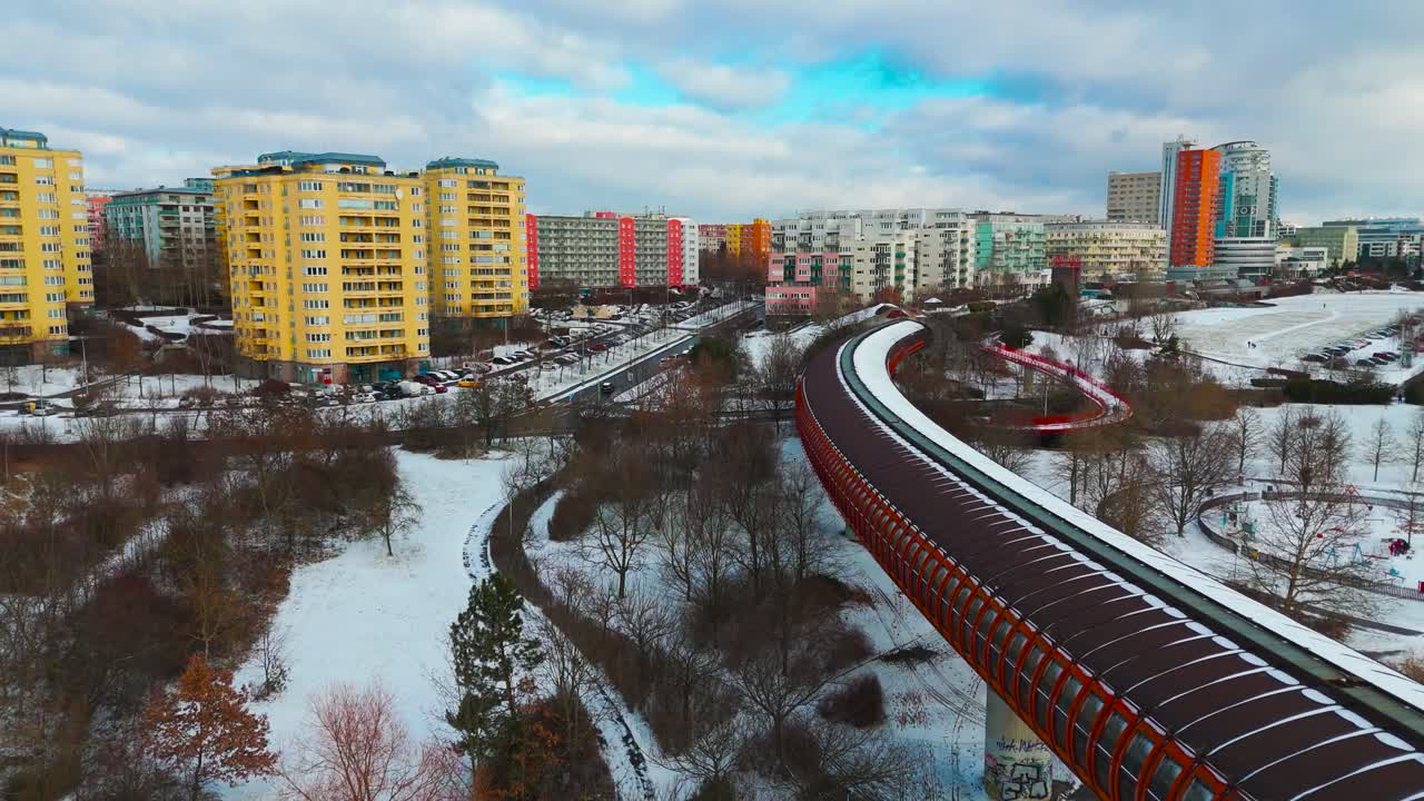 Aerial view of metro bridge winding through snowy suburban landscape, Prague