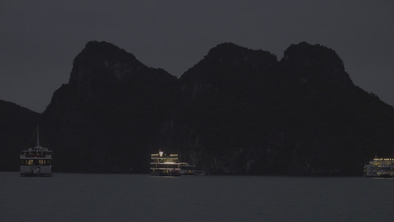 ベトナムのハ・ロング・ベイの山の背景に照らされた観光船 ⁇