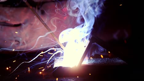 primer plano de un soldador trabajando en una pieza de metal