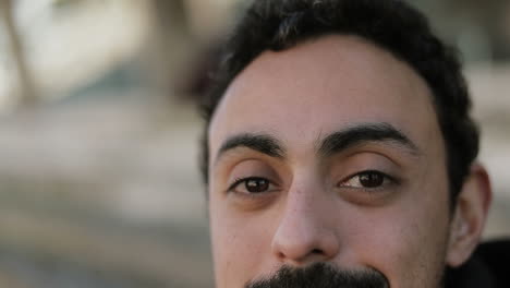 Front-view-of-young-Arabic-handsome-mans-face-with-dark-beard-looking-at-camera