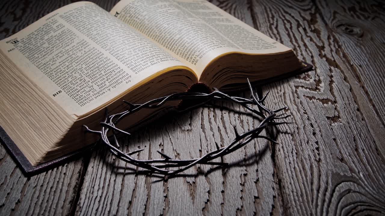 A dramatic, low-angle shot of an open Bible and crown of thorns on rustic wood, evoking a somber