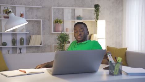Unhappy-and-overwhelmed-with-work-African-man-works-in-home-office-and-White-young-girlfriend-brings-his-coffee-and-gives-him-morale.