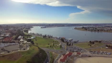 Toma-Aérea-De-Drones-De-La-Ciudad-De-Newcastle,-Revelando-La-Playa,-El-Puerto,-Fort-Scratchley-Y-Los-Muelles