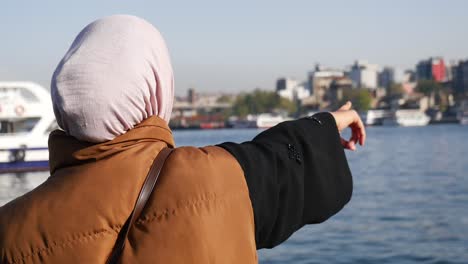 woman pointing to istanbul cityscape from the riverbank